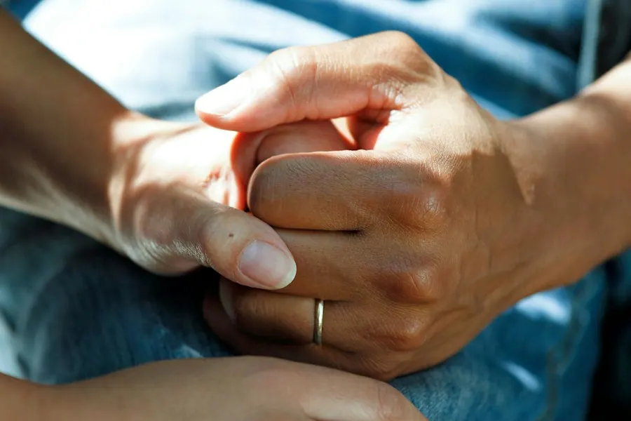 Close-up of a therapist holding a client's hands during a counseling session, mental health billing services