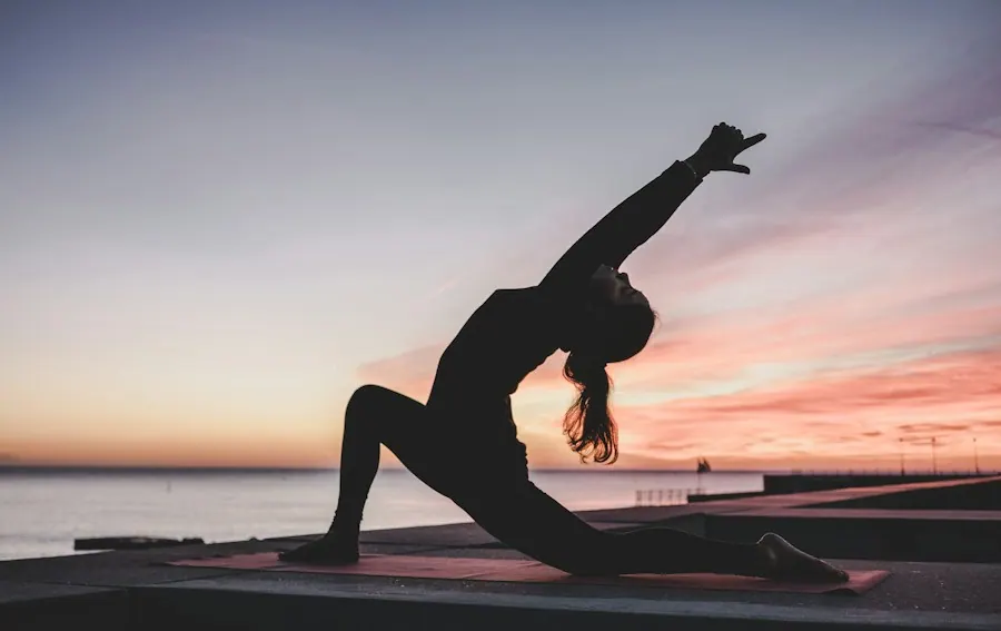 Silhouette of a person stretching in a low lunge on a mat at sunset by the water, chiropractic billing services